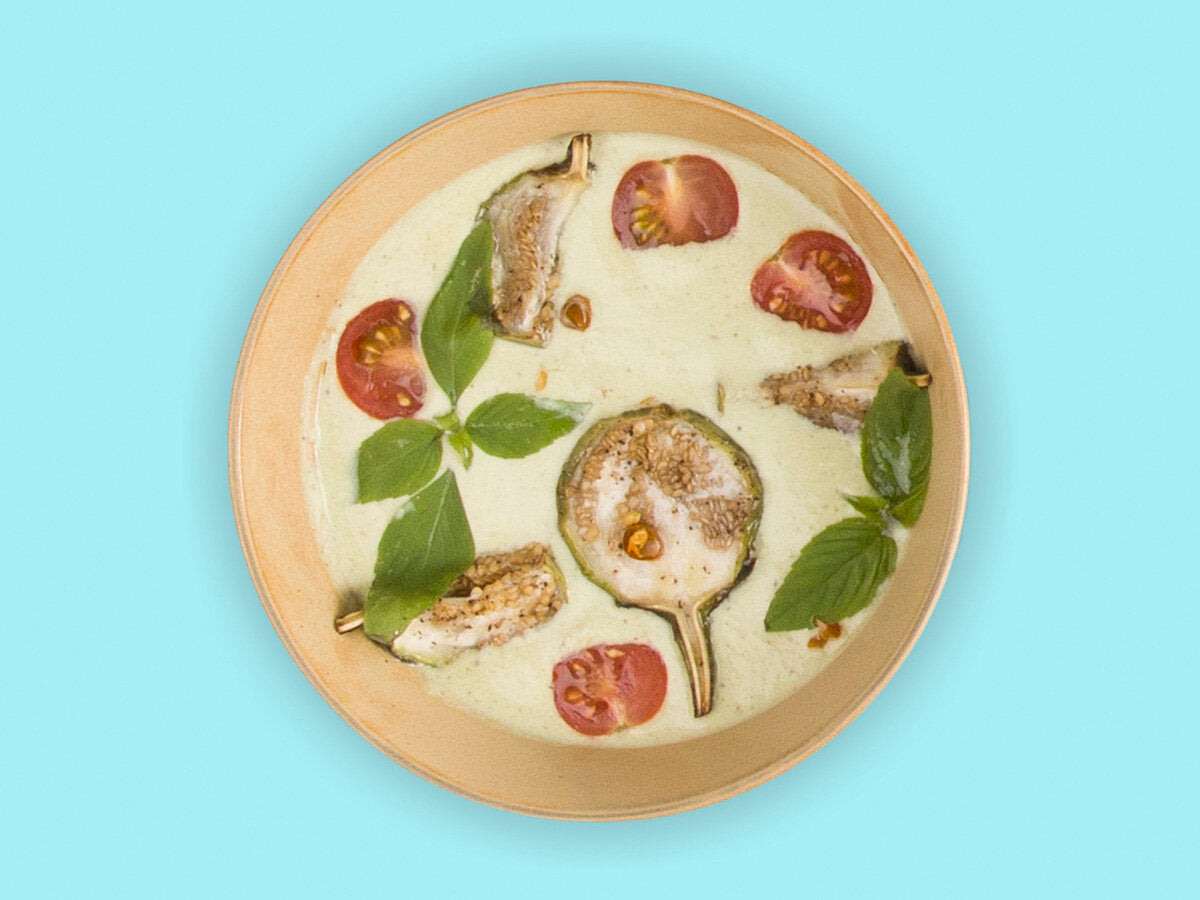 A plate of green curry in it with blue background