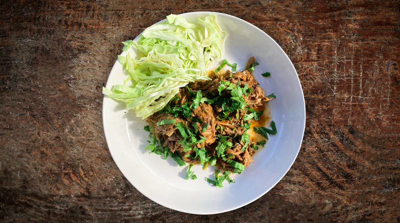 A white plate with vegetables and meat dish on it on the table