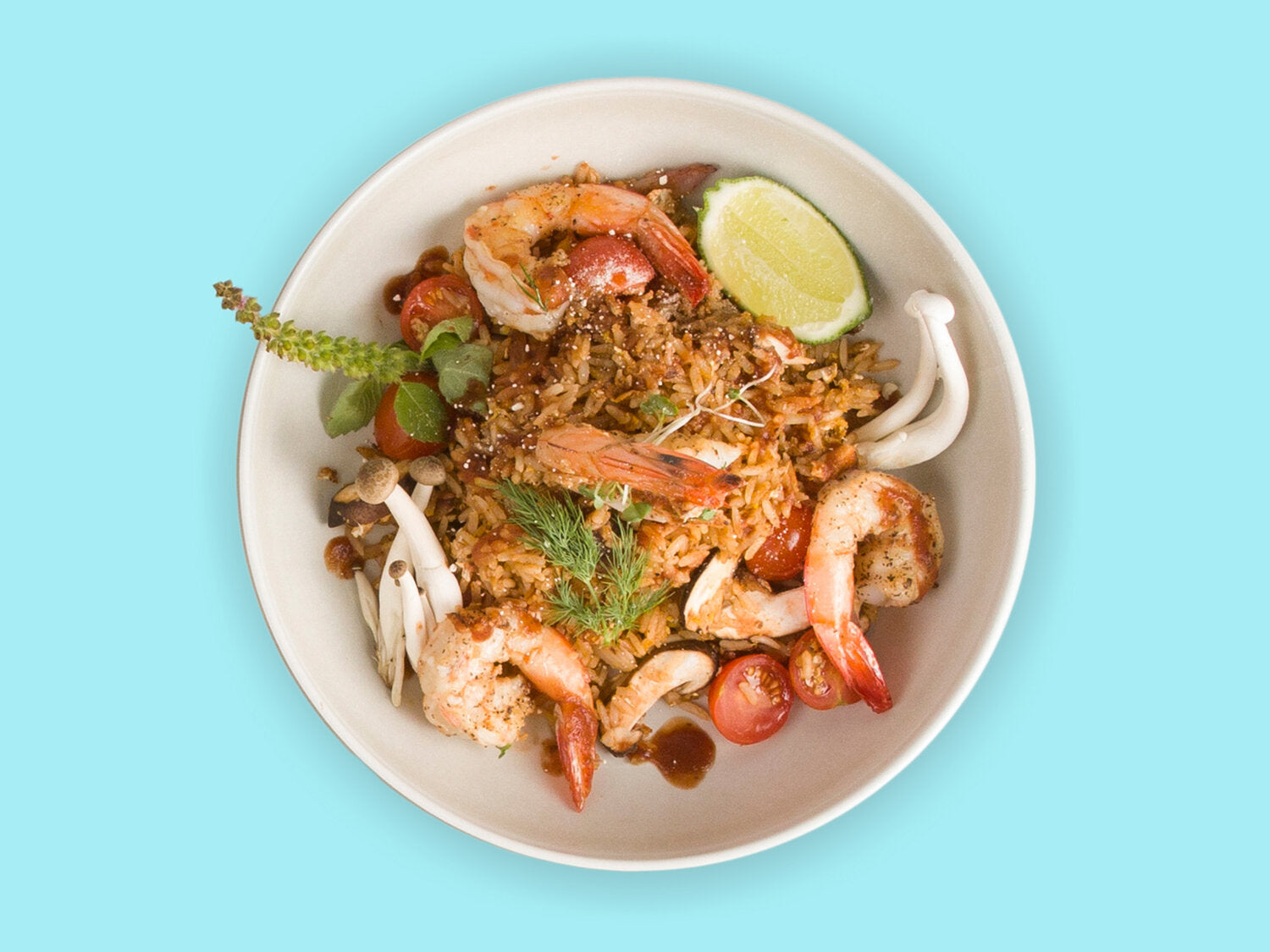 A white plate of shrimp with rice and vegetables in it on blue background can be seen.