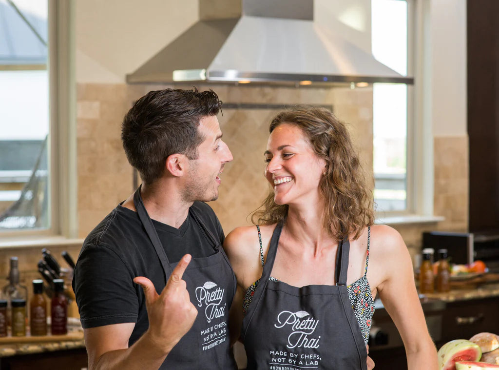 A photo of smiling couple wearing Pretty Thai apran